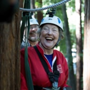 A woman on a zip line in the woods laughing