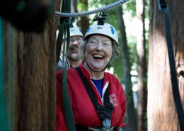 A woman on a zip line in the woods laughing