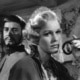 A still from Smiles of a Summer Night. A woman in the forefront raises a hand while a man stands behind her.