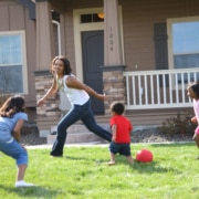 A mother runs around the yard with her three children