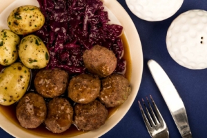 A large platter filled with meatballs, roasted potatoes, and shredded purple cabbage