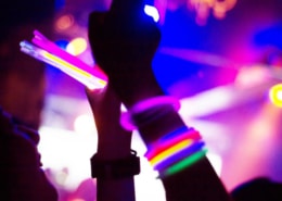 Hands covered with glow stick bracelets. They are having fun with taking pictures with mobile phone.