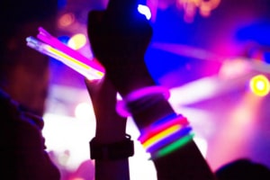 Hands covered with glow stick bracelets. They are having fun with taking pictures with mobile phone.