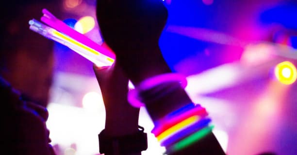 Hands covered with glow stick bracelets. They are having fun with taking pictures with mobile phone.