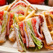 A triangularly sliced club sandwich on a large plate with french fries