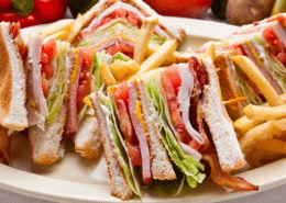 A triangularly sliced club sandwich on a large plate with french fries