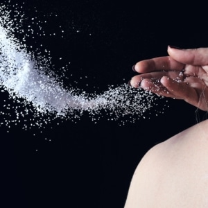 A person throws a large amount of salt over their shoulder