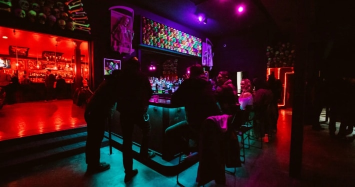 Interior of The Crypt. People are sitting at a neon bar