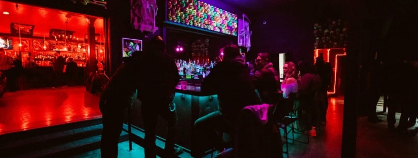 Interior of The Crypt. People are sitting at a neon bar