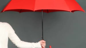 A person holds out an opened red umbrella indoors