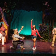 Little Red's mom, the Wolf, Little Red, and the Park Ranger sing onstage together. Everyone is looking at Little Red, who stands in the center, smiling.