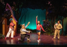 Little Red's mom, the Wolf, Little Red, and the Park Ranger sing onstage together. Everyone is looking at Little Red, who stands in the center, smiling.