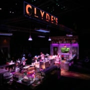 Clyde's glows in large lettering above the kitchen set. Four cooks are scattered about, prepping the kitchen.