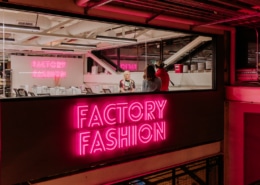 Factory Fashion glows in neon pink lettering outside the workshop in Stanley Marketplace.