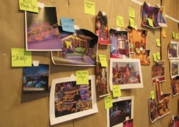 A number of photos and sticky notes cover a wall in Lonnie's studio. It's a sort of flow chart for the 2023 Camp Christmas.