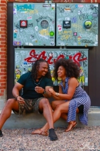 A couple sits together on a stoop, laughing.