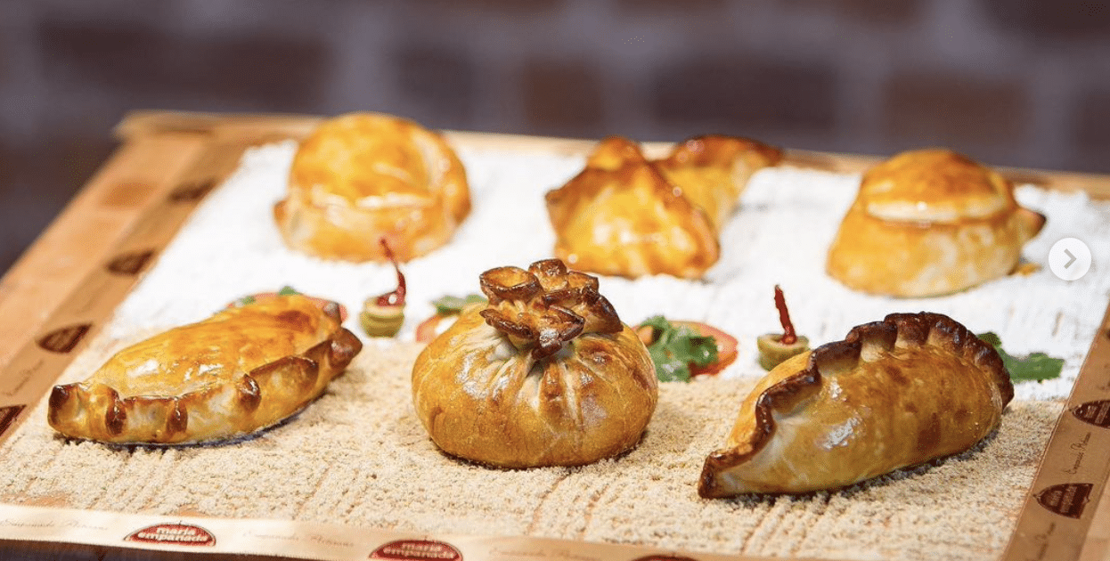 A row of select empanadas from Maria Empanada. Each is folded in a special way and toasted to a golden brown.