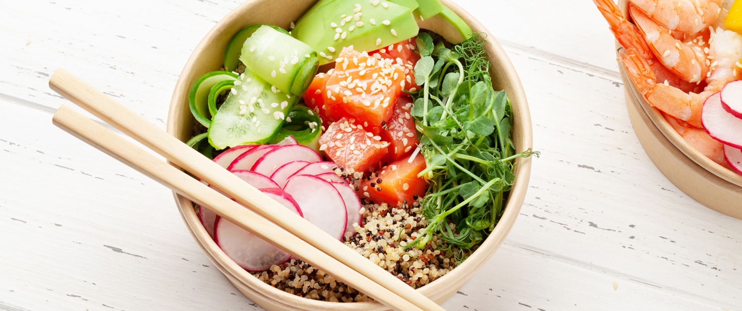 Poke bowl with sliced cucumber, slided radishes, tuna, rice, greens and chopsticks