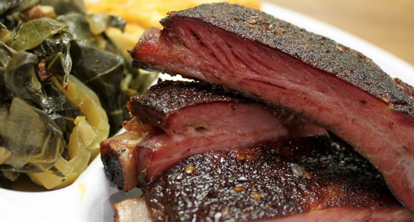 A plate of ribs and collard greens from Rolling Smoke BBQ in Stanley Marketplace