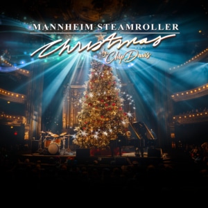 A graphic featuring a glowing, decorated Christmas tree onstage surrounded by instruments and illuminated by dramatic blue and white spotlights.White script reads Mannheim Steamroller Christmas by Chip Davis