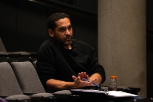 Playwright Terence Anthony sits in a theatre seat. An open binder holds his script for Godspeed.