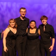 Camille, Caleb, Gabi, and Connor pose for a photo together, smiling. They are all in black formal wear.