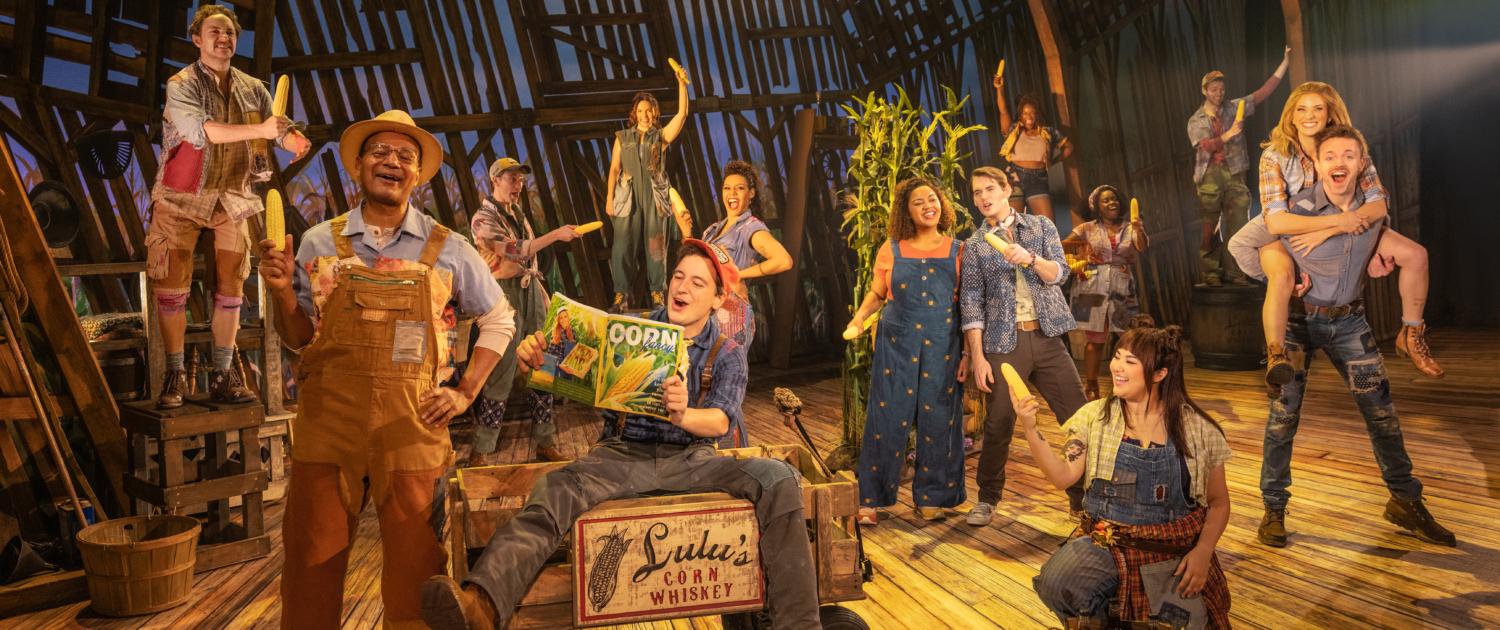 A group of actors on stage in overalls who resemble farmers.