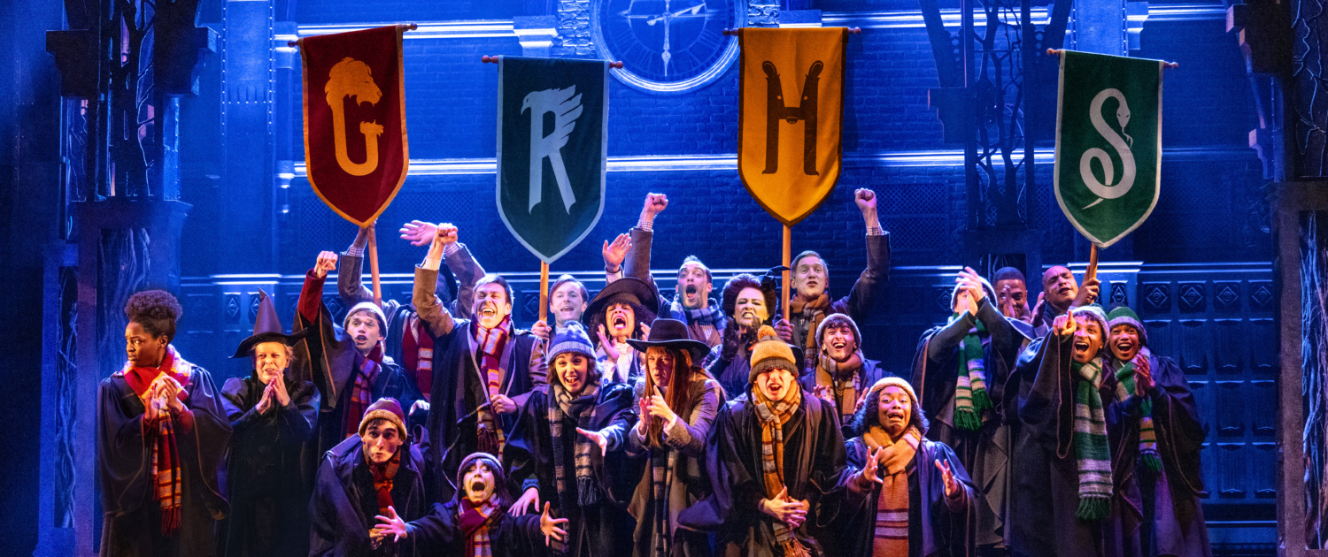 A group of children in long choir-like robes with stoles holding pennants with the letters G, R, H, and S.
