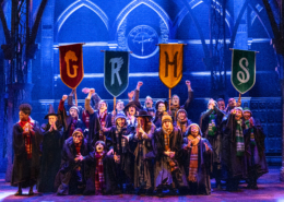 A group of children in long choir-like robes with stoles holding pennants with the letters G, R, H, and S.