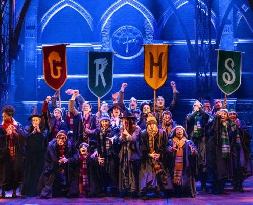 A group of children in long choir-like robes with stoles holding pennants with the letters G, R, H, and S.