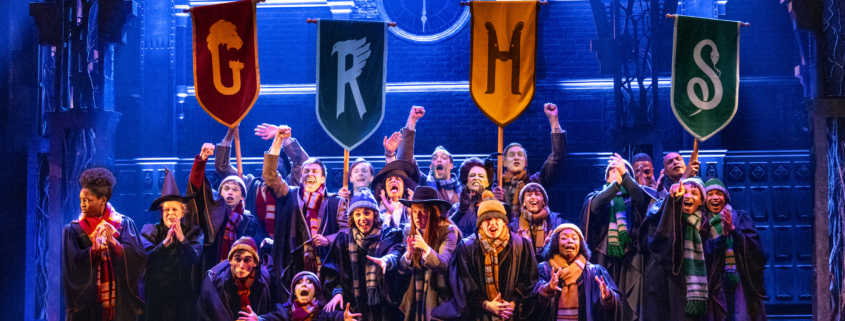 A group of children in long choir-like robes with stoles holding pennants with the letters G, R, H, and S.