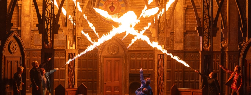 A stage production with bursts of fire filling what appears to be a cathedral