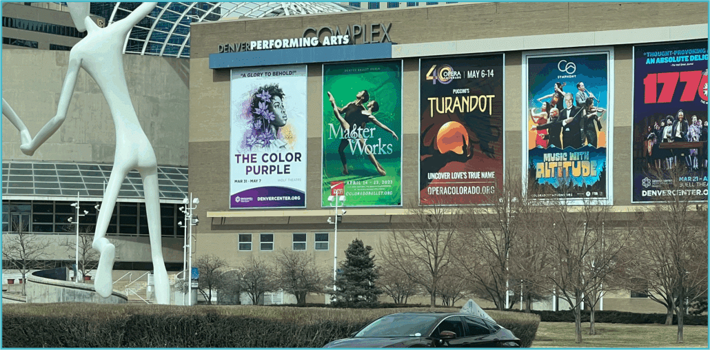 Side of a building with large banners advertising The Color Purple among other shows.