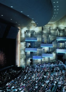 Interior of Buell Theatre before the show. Audience is seated facing the stage. 