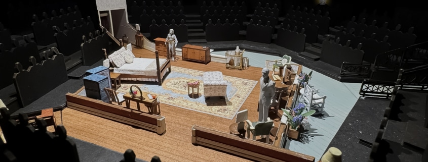 A set model of Cat on a Hot Tin Roof showing a bedroom in a Southern plantation with a bed, vanity, chaise lounge, rug, various chairs, and openings into a hallway and onto a veranda.