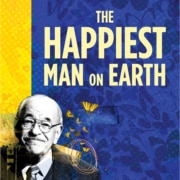 The title treatment in blue spelling "The Happiest Man on Earth" on top of a yellow background with birds and a barb wire fence in the background.