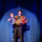 A circus ring leader holding a little person