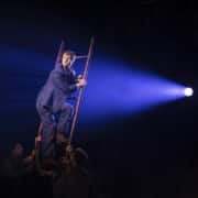 A circus performer high atop a ladder