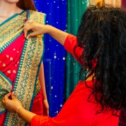 Brunette Indian woman choosing a new traditional sari that is red with green and gold trim