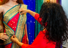 Brunette Indian woman choosing a new traditional sari that is red with green and gold trim