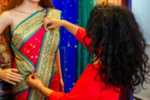 Brunette Indian woman choosing a new traditional sari that is red with green and gold trim