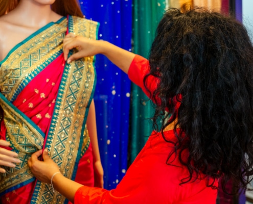 Brunette Indian woman choosing a new traditional sari that is red with green and gold trim