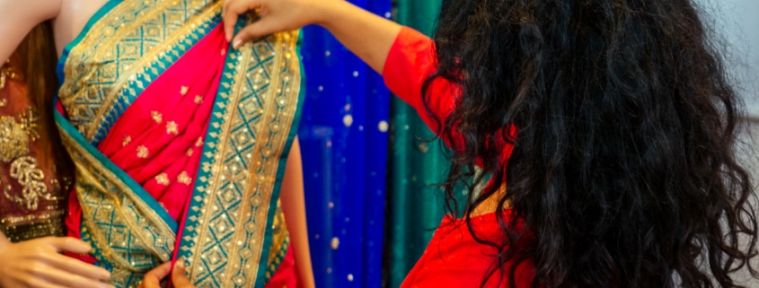 Brunette Indian woman choosing a new traditional sari that is red with green and gold trim