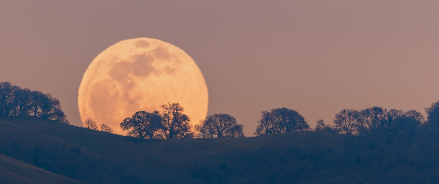 Full moon rising from behind a hill in the Diablo Mountain Range, in South San Francisco Bay Area, San Jose, California