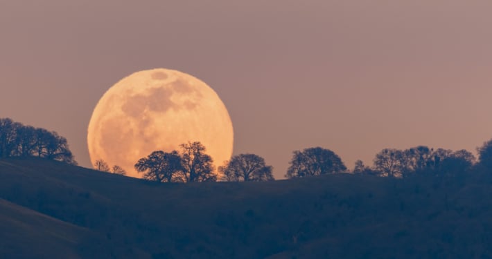 Full moon rising from behind a hill in the Diablo Mountain Range, in South San Francisco Bay Area, San Jose, California