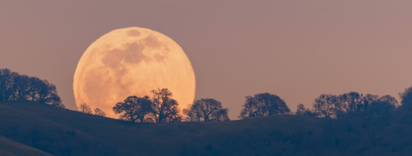 Full moon rising from behind a hill in the Diablo Mountain Range, in South San Francisco Bay Area, San Jose, California