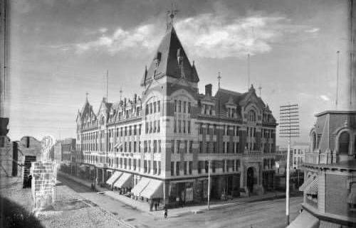 A black and white image of the historic Tabor Grand Opera House in Denver Colorado, which was five-stories, covered a square city block and had a rounded peak at one corner.