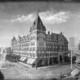 A black and white image of the historic Tabor Grand Opera House in Denver Colorado, which was five-stories, covered a square city block and had a rounded peak at one corner.