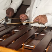Two individuals in white playing a marimba