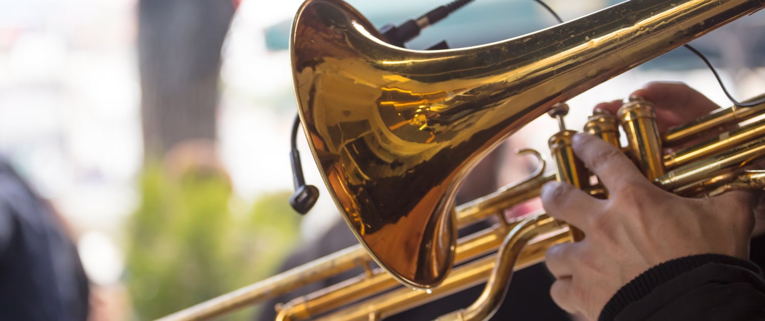 Close up image of a trombone being held by someone in an outdoot setting.